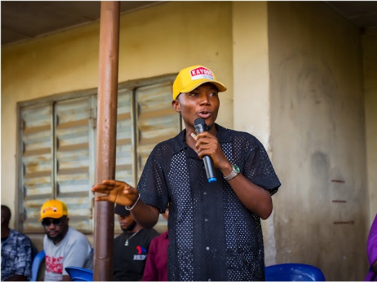 Kayode Hamzat speaking into a microphone at a community meeting