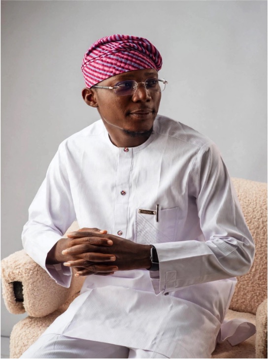 Kayode Hamzat seated in white agbada and a patterned cap